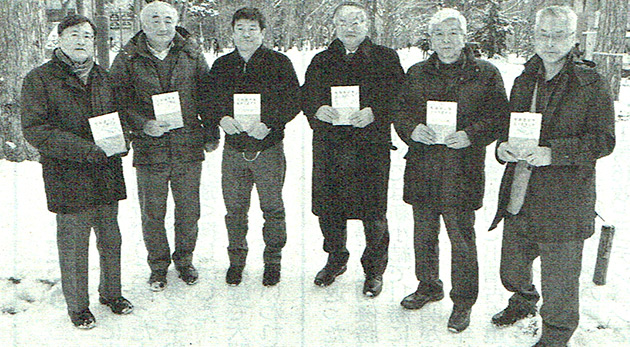 冊子を持つ山形助教（左から3人目）ほか執筆者